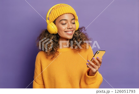 A Young Woman Smiles as She Listens to Music on Her Smartphone A Young Woman Smiles as She Listens to Music on Her Smartphone 126051793