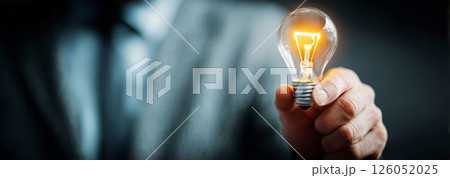 Businessman Holding Lit Light Bulb Symbolizing New Ideas in Modern Office Setting 126052025
