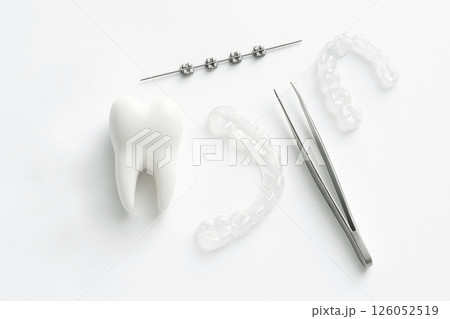 Tooth with orthodontic tools on white background. Dental treatment, alignment, and oral healthcare. 126052519