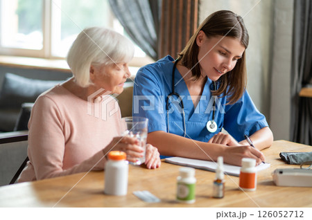 Woman providing health care and assistance to aged patient offering treatment and medication 126052712