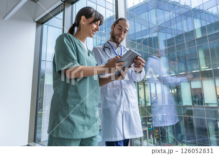 Two doctors discussing an interesting case while walking in the clinic corridor Two doctors discussing an interesting case while walking in the clinic corridor 126052831