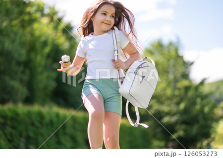 Happy little girl running outside holding delicious waffle cone enjoying cool ice cream 126053273