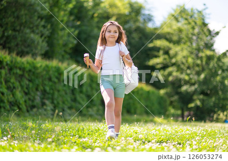 Little girl eating cold ice cream while running 126053274