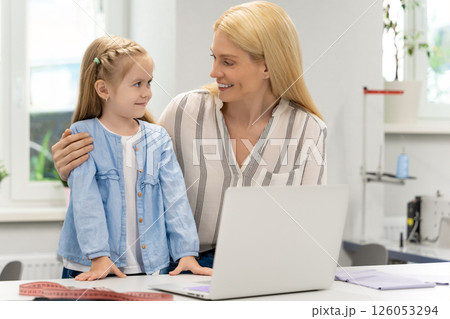 Pretty young caucasian woman in her design studio with her daughter Pretty young caucasian woman in her design studio with her daughter 126053294