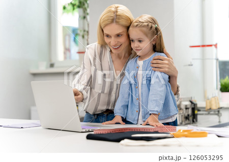 Pretty young caucasian woman in her design studio with her daughter Pretty young caucasian woman in her design studio with her daughter 126053295