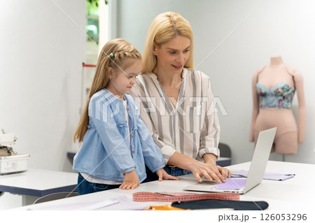 Pretty young caucasian woman in her design studio with her daughter Pretty young caucasian woman in her design studio with her daughter 126053296