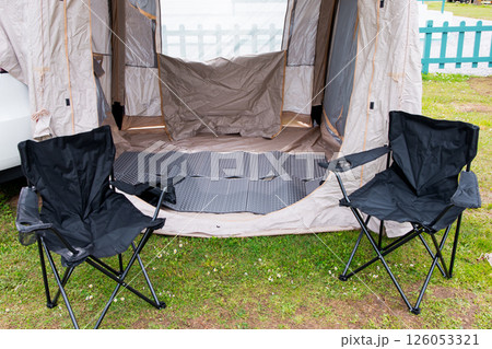 Camping setup with tent and chairs on green grass outdoors Camping setup with tent and chairs on green grass outdoors 126053321