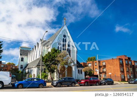 Old Holy Virgin Cathedral of the Russian Orthodox Church stands with its distinct gothic design, surrounded by urban residences and street traffic under clear skies. 126054117