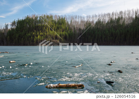 Rocky Cliff Above Frozen Lake with Pine Trees in Early Spring 126054516