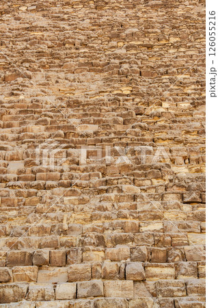 Historic stone facade of a pyramid showcasing ancient construction techniques in Egypt during the daytime 126055216