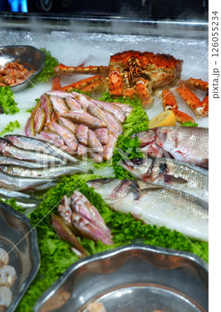 Fresh seafood display at a bustling market showcasing various fish and shellfish on ice 126055234