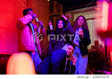 Friends enjoying a night out with drinks at a vibrant bar during a lively evening gathering 126055270