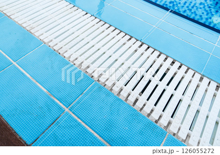 Modern swimming pool design with textured tiles and white slats enhancing aesthetics and safety features 126055272