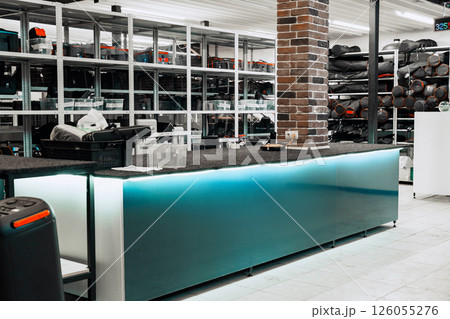 Modern interior design of a busy retail store featuring a sleek counter with storage and organized inventory on shelves Modern interior design of a busy retail store featuring a sleek counter with storage and organized inventory on shelves 126055276