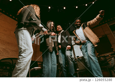 Friends enjoying a lively night of dancing and laughter at a cozy cafe during the weekend evening Friends enjoying a lively night of dancing and laughter at a cozy cafe during the weekend evening 126055280