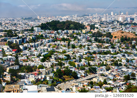 Densely packed residential neighborhoods of San Francisco viewed from above, showing colorful houses on steep hills, Sutro Forest in the middle distance, and a fog-covered skyline in the background on Densely packed residential neighborhoods of San Francisco viewed from above, showing colorful houses on steep hills, Sutro Forest in the middle distance, and a fog-covered skyline in the background on 126055520