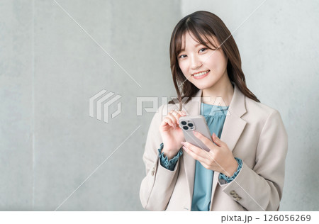 スマホを操作するスーツ姿の若いアジア人ビジネスウーマン スマホを操作するスーツ姿の若いアジア人ビジネスウーマン 126056269