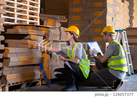 Operational or general worker man and women yellow hardhat using check quality and stock cardboard product. Large industry in paper production line warehouse. Operational or general worker man and women yellow hardhat using check quality and stock cardboard product. Large industry in paper production line warehouse. 126057377