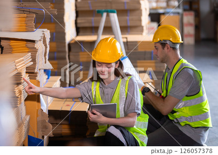 Operational or general worker man and women yellow hardhat using check quality and stock cardboard product. Large industry in paper production line warehouse. Operational or general worker man and women yellow hardhat using check quality and stock cardboard product. Large industry in paper production line warehouse. 126057378