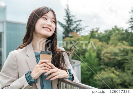 屋上でコーヒーを飲みながら気分転換するスーツ姿の若いアジア人女性 屋上でコーヒーを飲みながら気分転換するスーツ姿の若いアジア人女性 126057388