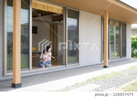 軒先や縁側で抱っこでくつろぐ母親と娘(子供)子育ての幸せのイメージ広角の全身 軒先や縁側で抱っこでくつろぐ母親と娘(子供)子育ての幸せのイメージ広角の全身 126057475