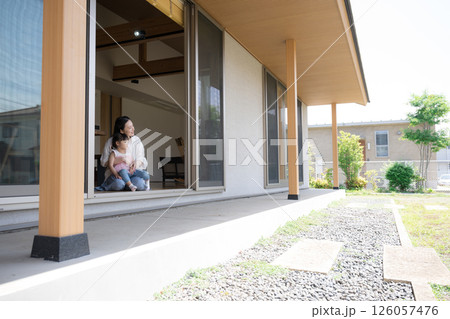 軒先や縁側で抱っこでくつろぐ母親と娘（子供）子育ての幸せのイメージ広角の全身 126057476