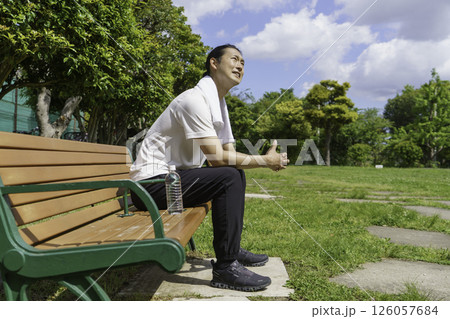 公園のベンチに座って水分補給をする若い男性 126057684