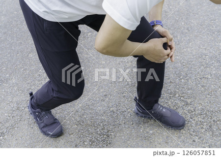 ランニング中膝が痛くなり膝を抱える若い男性の足元 126057851