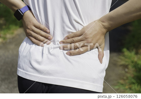 ランニング中腰が痛くなり腰に手を当てる若い男性の足元 腰痛 ランニング中腰が痛くなり腰に手を当てる若い男性の足元 腰痛 126058076