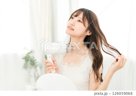 ヘアドライヤーでヘアブロー・髪の毛を乾かす女性（ヘアケア） 126059068
