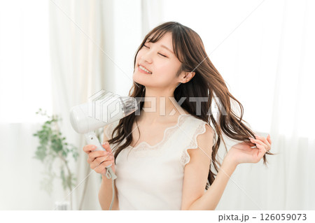 ヘアドライヤーでヘアブロー・髪の毛を乾かす女性（ヘアケア） 126059073