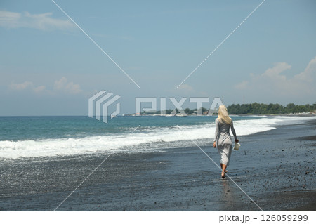 Young woman walking on black sand beach, space for text Young woman walking on black sand beach, space for text 126059299