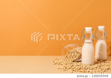 Bottles of alternative milk and soybeans on orange background, space for text Bottles of alternative milk and soybeans on orange background, space for text 126059309