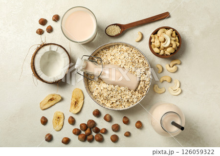 Bottles and glass of milk, bowl with oatmeal and herbal ingredients on light background, top view 126059322