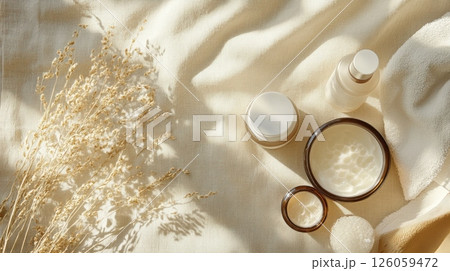 Natural skincare products on linen fabric with soft sunlight and dry flowers. Cream jars, spray bottle, towel, and spa sponge for organic beauty routine AI generated 126059472