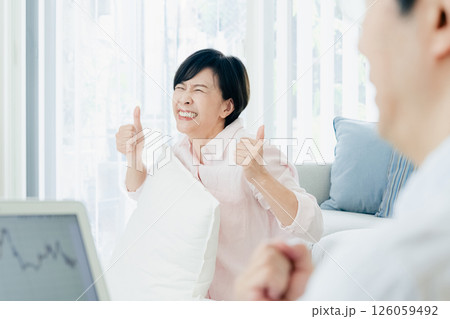 リビングでパソコンを見て喜ぶ中高年夫婦 リビングでパソコンを見て喜ぶ中高年夫婦 126059492