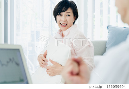 リビングでパソコンを見て喜ぶ中高年夫婦 リビングでパソコンを見て喜ぶ中高年夫婦 126059494