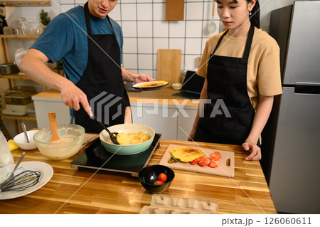 Man and woman making homemade pancakes and slicing fruits for a cozy meal at home 126060611