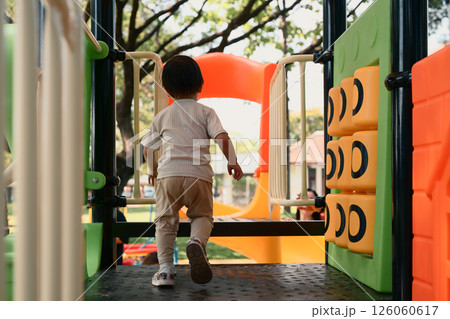 Back view of toddler enjoying playtime at a colorful outdoor playground Back view of toddler enjoying playtime at a colorful outdoor playground 126060617
