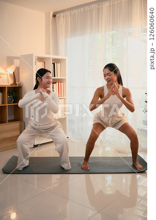 Mother and daughter enjoying a workout session together in a bright, cozy home 126060640