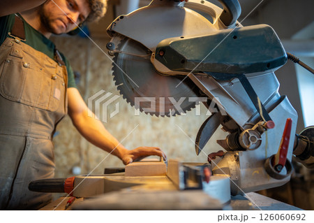 Eperienced woodworker use mitre saw, slice wood blocks for project. Craftsmanship, blade control Eperienced woodworker use mitre saw, slice wood blocks for project. Craftsmanship, blade control 126060692