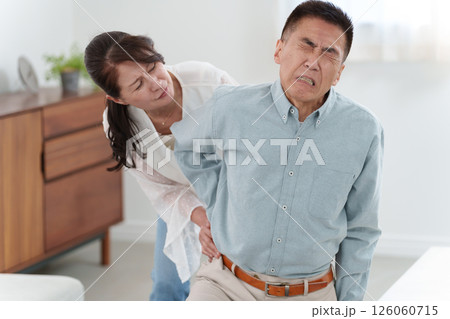 ぎっくり腰のシニア男性とサポートするシニア女性 126060715