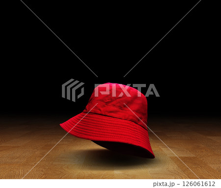Red bucket hat on wooden floor, black background. Red bucket hat on wooden floor, black background. 126061612