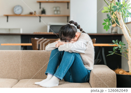 ソファで泣く小学生,中学生の女の子（落ち込む,体調不良,不登校,ストレス） 126062049