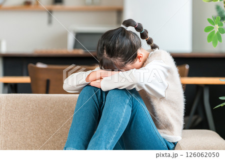 ソファで泣く小学生,中学生の女の子（誹謗中傷,ひとりぼっち,虐待,いじめ）） 126062050