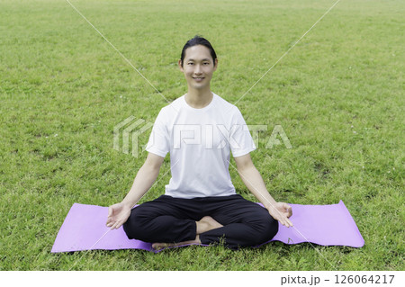 公園の芝生の上でヨガをする若い男性 公園の芝生の上でヨガをする若い男性 126064217