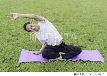 公園の芝生の上でヨガをする若い男性 公園の芝生の上でヨガをする若い男性 126064663