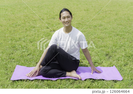 公園の芝生の上でヨガをする若い男性 126064664