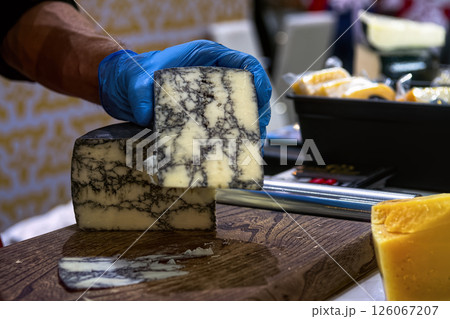 Seller slicing mold cheese on wooden board. Cheese shop. 126067207