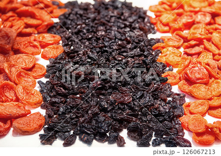Orange dried apricots and dark raisins isolated on white background top view. Dried fruits background. Orange dried apricots and dark raisins isolated on white background top view. Dried fruits background. 126067213